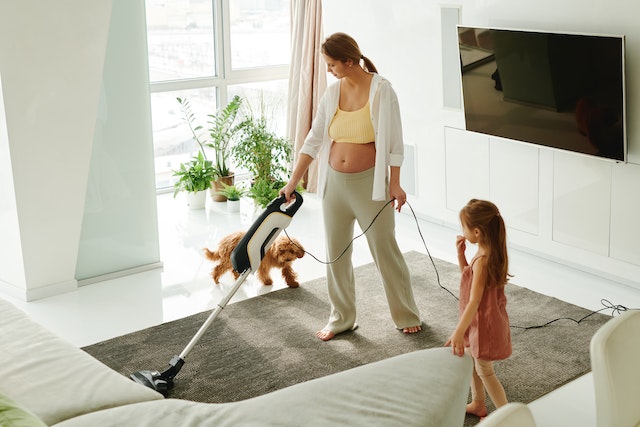 Woman vacuuming with a child in a living room
